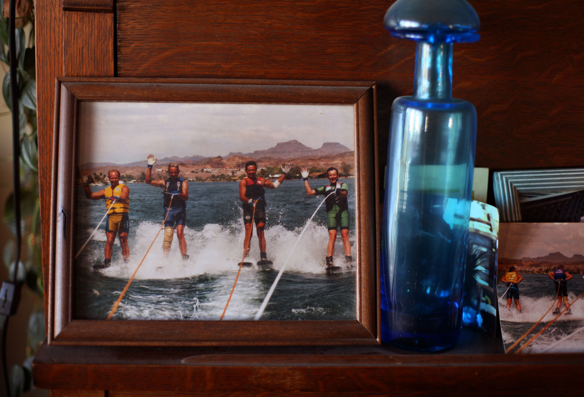 Photographs and antique bottles line the shelves inside Johnny O’s home. He’s second from left here in his younger days on the water, where he is the happiest.