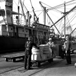 Longshoremen load cargo from a rolling pallet onto a ship anchored by the dock at the Port of Los Angeles in 1939. Courtesy: WPA collection at the Los Angeles Public Library